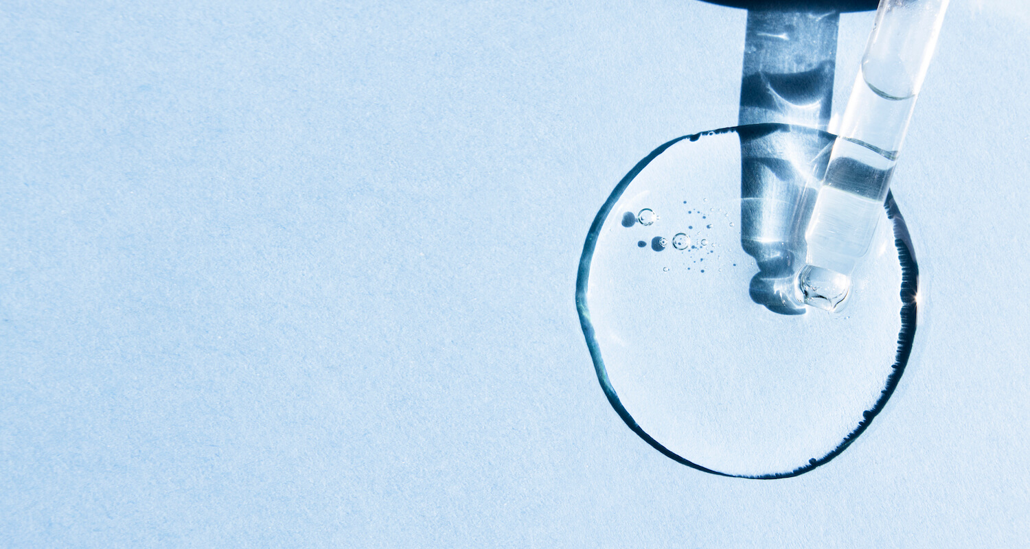 transparent-acid-body-serum-close-up-on-a-blue-ba-2022-05-31-05-28-03-utc